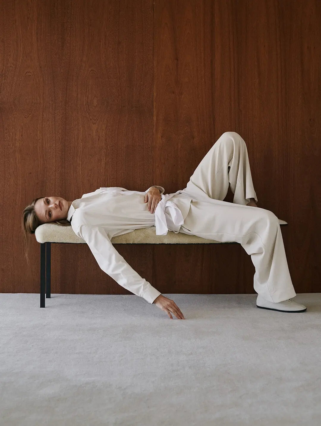 Model is laying down in white matching pants and top